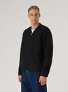 A model in a Black Wool Fleece Zip Bomber on a white background. The bomber is paired with blue jeans. The fleece has a visible texture.