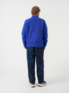 Angled view of a model wearing the Blue Wool Fleece Zip Bomber Jacket in a light studio setting. Highlights the jacket side profile, ribbed cuff construction, zipper closure, and deep blue wool fleece material.