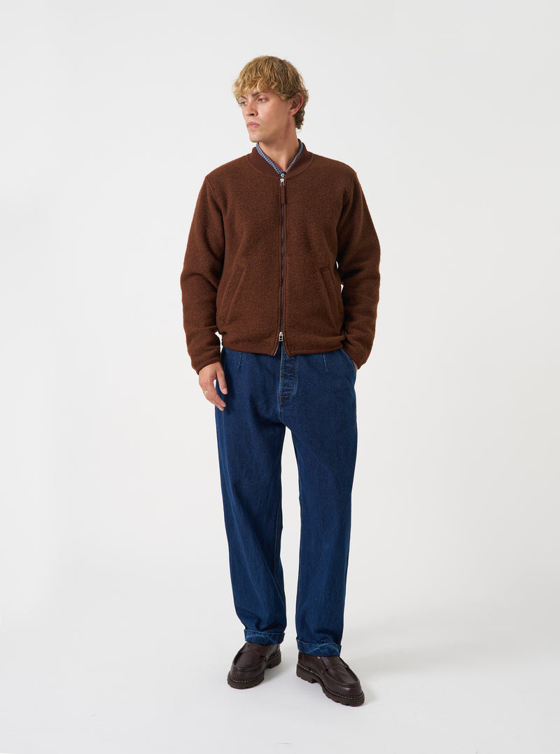 Front view of a model wearing the Cacao Wool Fleece Zip Bomber Jacket in a studio setting with a light backdrop. The model stands facing front, showing the dark cacao brown fleece jacket, front zipper, and trim.