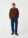 Front view of a model wearing the Cacao Wool Fleece Zip Bomber Jacket in a studio setting with a light backdrop. The model stands facing front, showing the dark cacao brown fleece jacket, front zipper, and trim.
