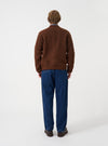 Angled side view of a model wearing the Cacao Wool Fleece Zip Bomber Jacket in a studio setting. Demonstrates the fit, side profile, deep brown wool fleece fabric, ribbed trim details, and overall silhouette.