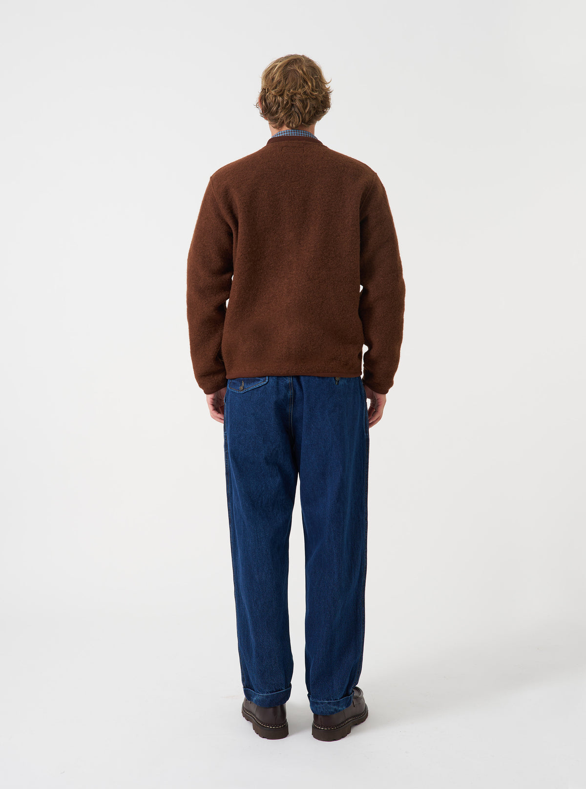 Angled side view of a model wearing the Cacao Wool Fleece Zip Bomber Jacket in a studio setting. Demonstrates the fit, side profile, deep brown wool fleece fabric, ribbed trim details, and overall silhouette.