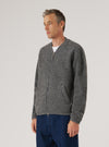 Male model wearing a grey marl wool fleece zip bomber, zipped fully closed, over a white crew-neck T-shirt and navy jeans. The bomber has a ribbed collar, full-length silver zip, a visible welt pocket at the hip, ribbed cuffs and hem. Textured boiled wool fleece fabric throughout. Grey seamless studio backdrop. Three-quarter front view, cropped at mid-thigh.