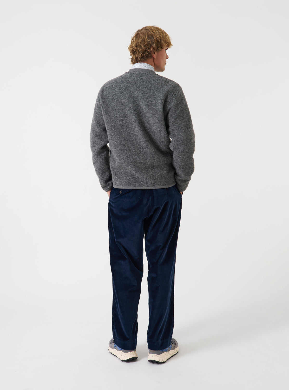 Angled side view of a model wearing the Grey Marl Wool Fleece Zip Bomber Jacket in a studio setting. The shot highlights the grey marl fabric texture, ribbed cuffs and collar, zip front, and side profile fit.