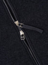 Close-up detail of the double zip fastening on a navy wool fleece bomber jacket. Two silver-tone metal zip sliders sit centrally, with black plastic teeth and a dark woven zip pull tab. The brushed wool fleece fabric texture is visible across the frame.