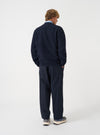 Angled view of a model wearing the Navy Wool Fleece Zip Bomber Jacket in a light studio setting. The model poses at a side angle, showcasing the dark navy fleece texture, zipped closure, and sleeve design.