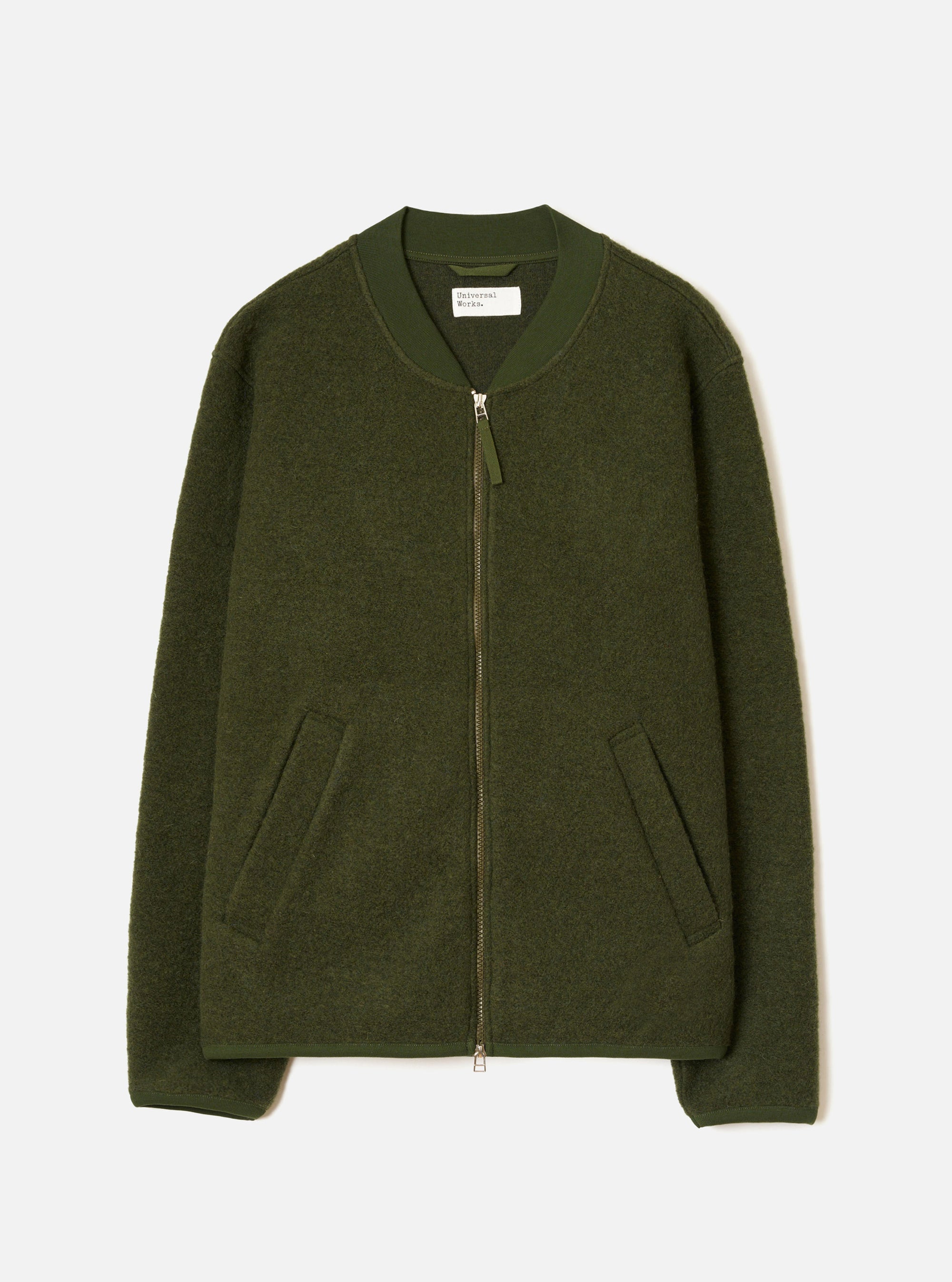 Olive wool fleece zip bomber, flat lay on a light grey seamless backdrop. Features a ribbed bomber collar, full-length silver zip with a fabric puller, and two welt hand pockets at the hem. The textured boiled wool fleece body contrasts with smoother ribbed cuffs and hem. A Universal Works woven label is visible at the neck.