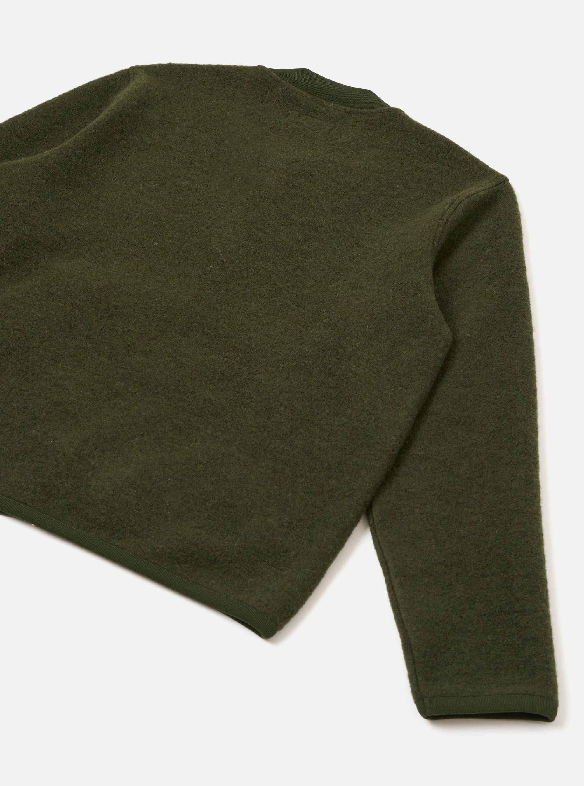 Olive wool fleece zip bomber laid flat on a white studio surface, shot from above at an angle. The image shows the upper back and right sleeve. The fabric has a dense, brushed fleece texture throughout. A smooth ribbed hem is visible at the base, with a plain ribbed cuff at the sleeve end.