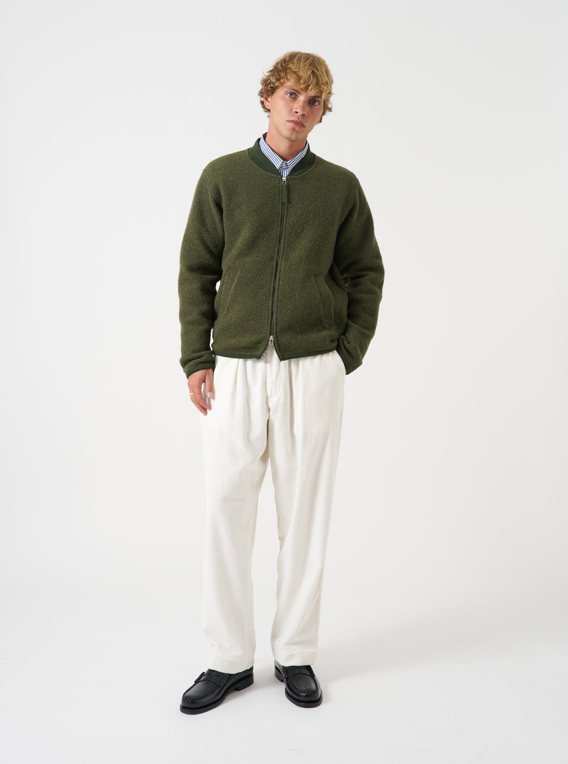 Front view of a model wearing the Olive Wool Fleece Zip Bomber Jacket in a light studio backdrop. The model faces forward, showing the olive green wool fleece jacket, full zip closure, ribbed cuffs, and collar.