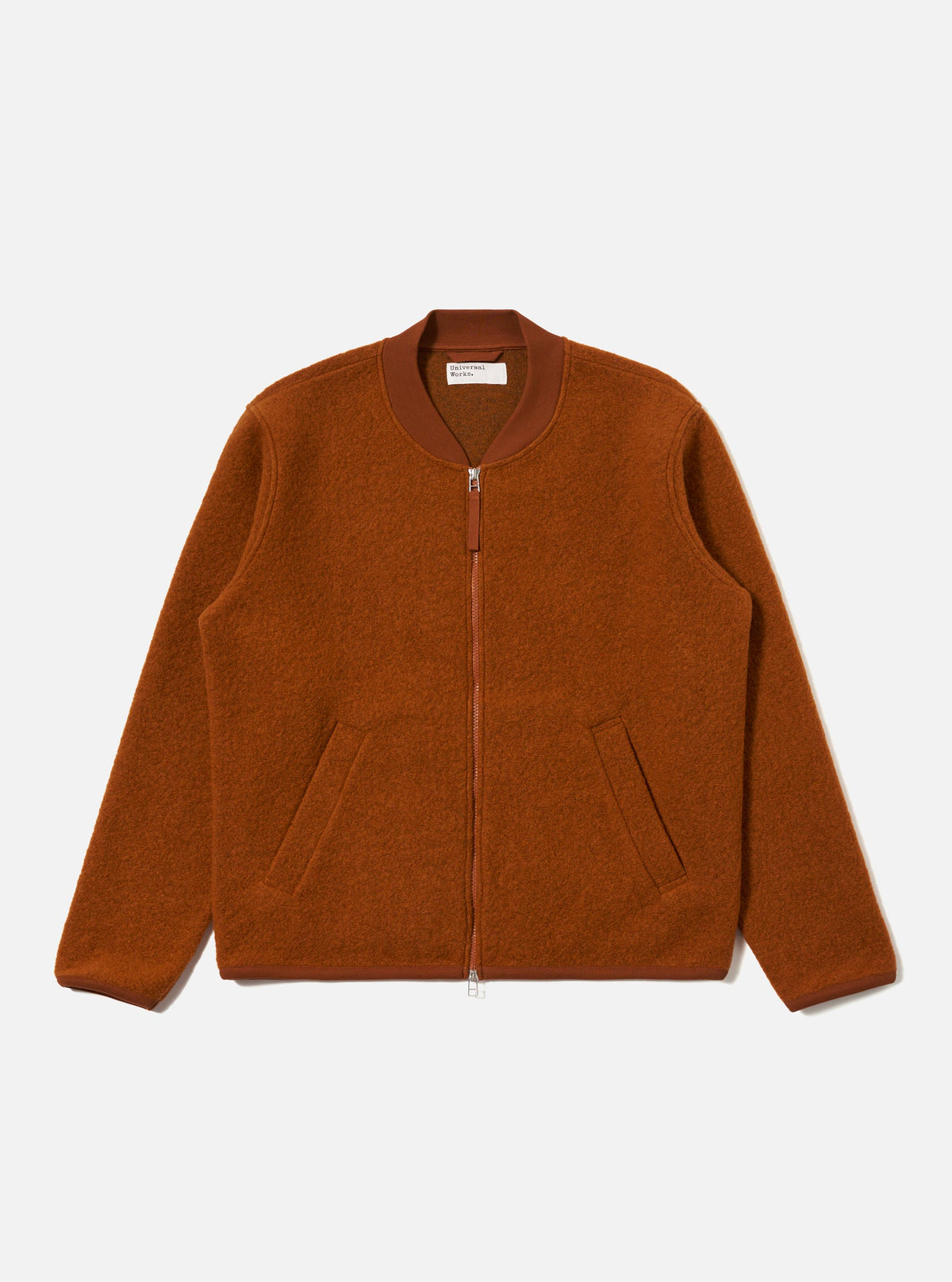 The Rust Wool Fleece Zip Bomber jacket in rust color, laid flat on a white background. The bomber has a zip front and pockets.