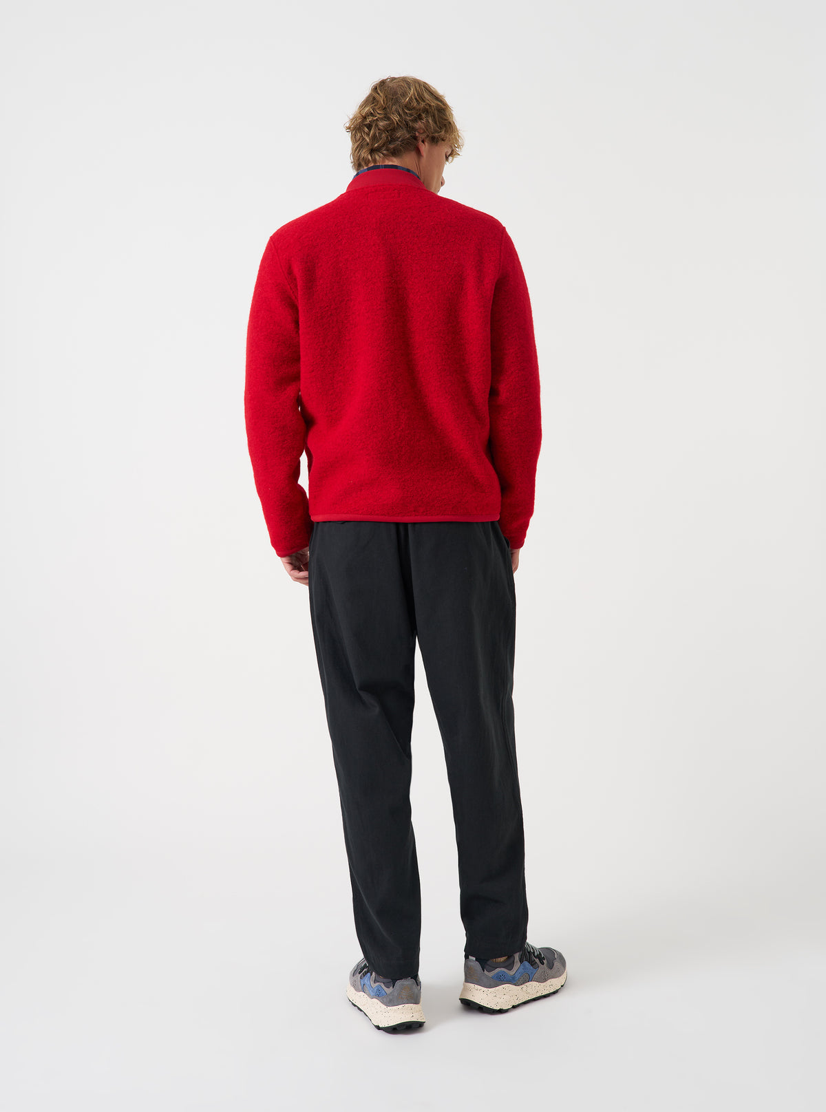 Back view of a model wearing the Scarlet Wool Fleece Zip Bomber Jacket in a studio setting. The model stands angled away, showcasing the rear cut, soft scarlet wool fleece texture, hem, and comfortable relaxed fit.
