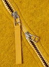 Close-up of the Yellow Wool Fleece Zip Bomber, showcasing the texture of the wool and the zipper detail. The background is a plain surface.
