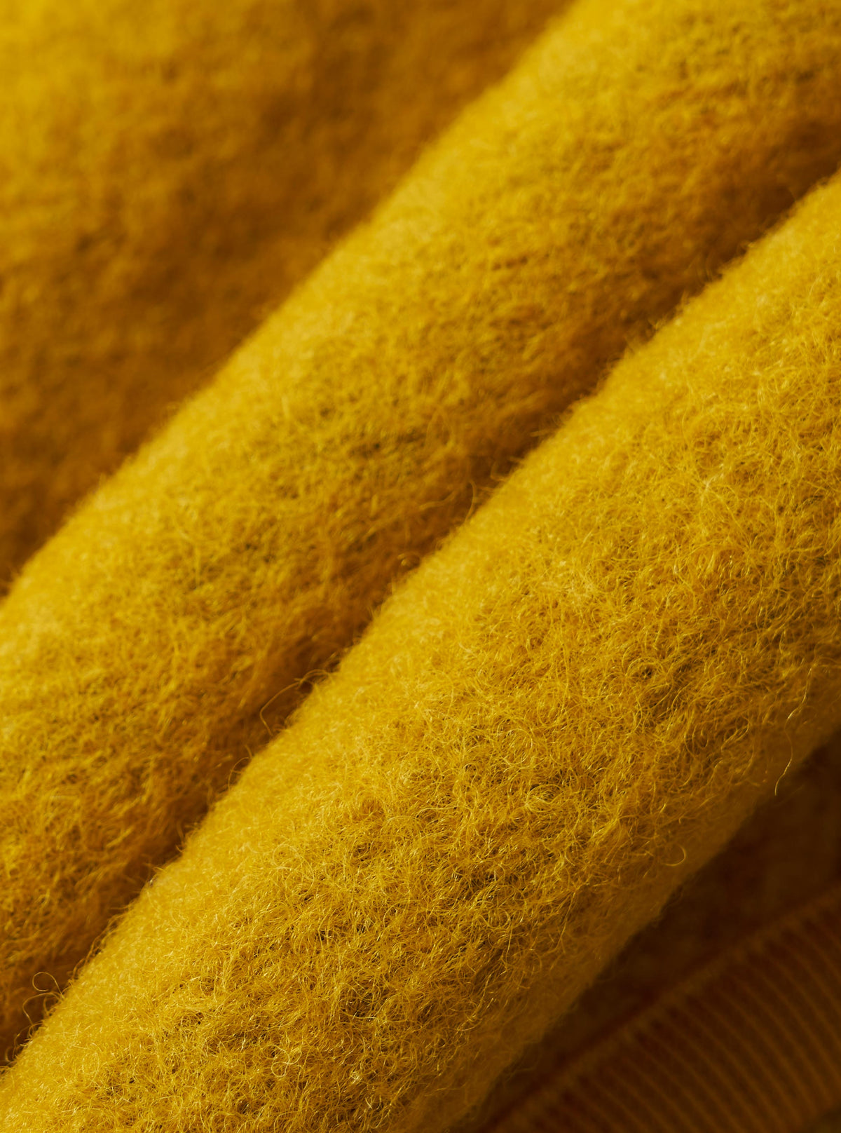 Close-up of the Yellow Wool Fleece Zip Bomber, showcasing the texture and color of the wool fleece material. The image is tightly cropped to highlight the fabric's details.