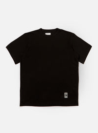 The Black Single Jersey Core Tee is displayed on a white background. The tee is a solid black color and has a relaxed fit.