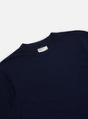 Close-up of the Navy Single Jersey Core Tee on a white surface. The tee is a dark navy color and made of a soft, single jersey material. The fit is relaxed and comfortable.