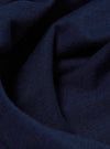 Close-up of the Navy Single Jersey Core Tee fabric. The soft, textured material is draped on a flat surface, showcasing its rich navy color and fine knit.
