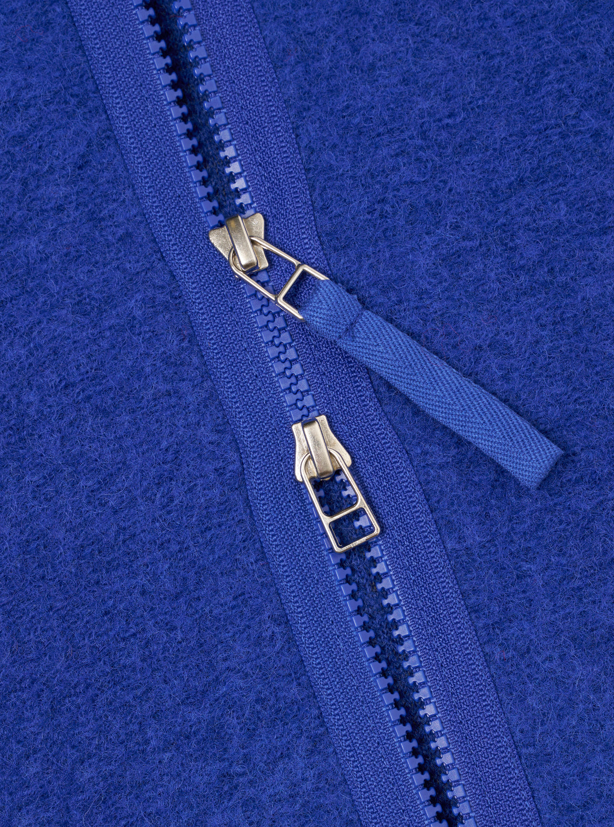 Close-up detail shot of the Blue Wool Fleece Zip Liner Jacket against a plain background. Focuses on the front zipper hardware, bound neck edge, and rich blue wool fleece fabric texture of the piece.