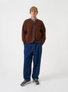 Front view of a model wearing the Cacao Wool Fleece Zip Liner Jacket in a studio setting. The model stands facing forward, displaying the brown wool fleece material, central front zip, collarless neck, and relaxed layer fit.