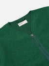 Close-up of the green Wool Fleece Zip Liner Jacket on a white background. The jacket is made of green wool fleece and has a silver zipper. A white label is visible.