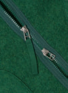 Close-up of the green wool fleece zip liner jacket, showcasing the texture and zipper detail. The jacket is laid flat on a neutral surface.
