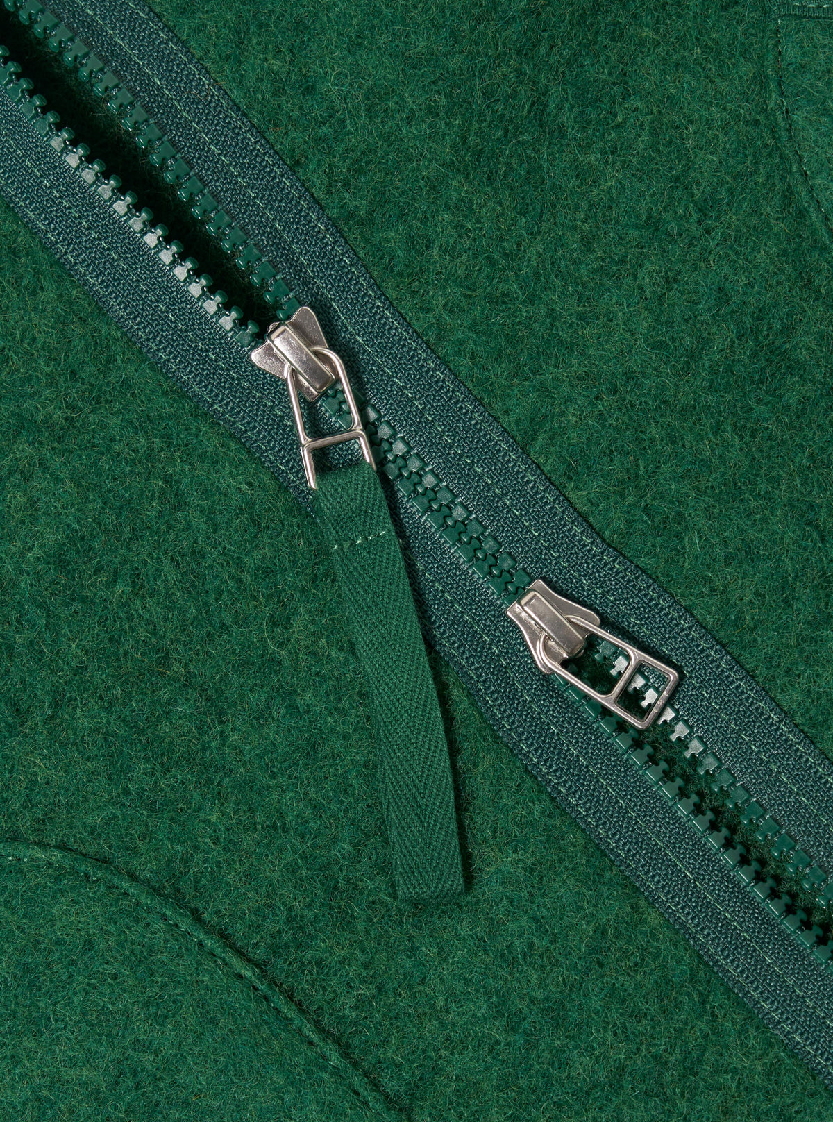 Close-up of the green wool fleece zip liner jacket, showcasing the texture and zipper detail. The jacket is laid flat on a neutral surface.