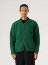 A model on a white background wears a Green Wool Fleece Zip Liner Jacket. The jacket is zipped and has pockets. The model wears a black shirt and pants.