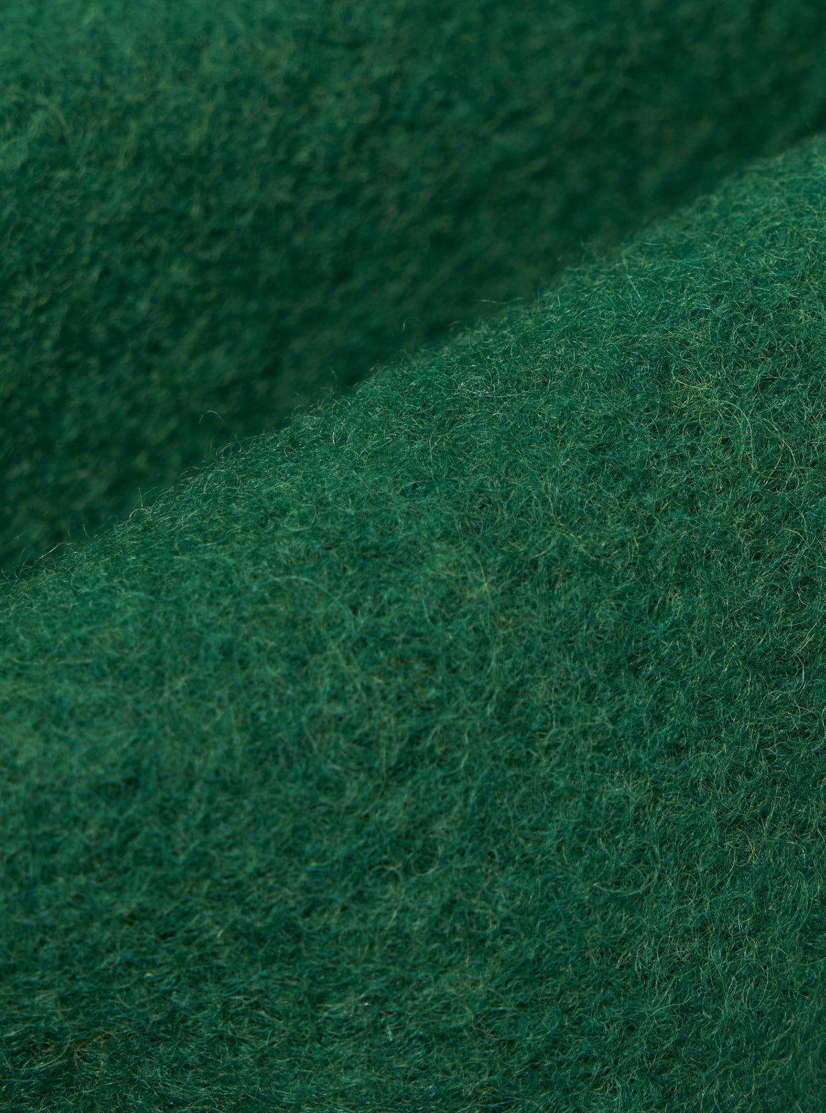 Close-up of the Green Wool Fleece Zip Liner Jacket material. The soft, green wool fleece is neatly folded to showcase its texture and quality.