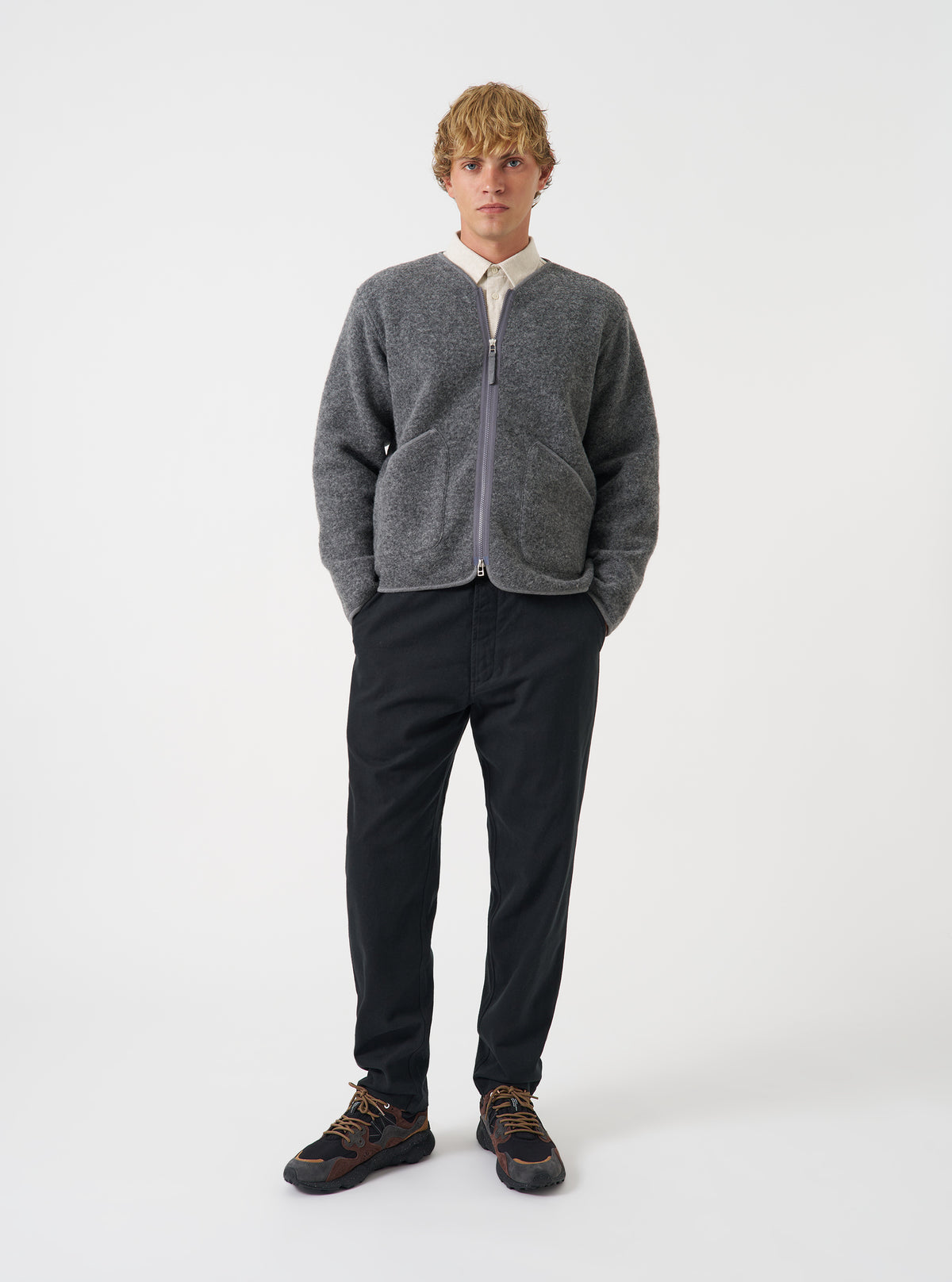 Front view of a model wearing the Grey Marl Wool Fleece Zip Liner Jacket in a plain studio setting. The model faces forward, presenting the mottled grey fleece fabric, full front zipper, and practical front pockets.