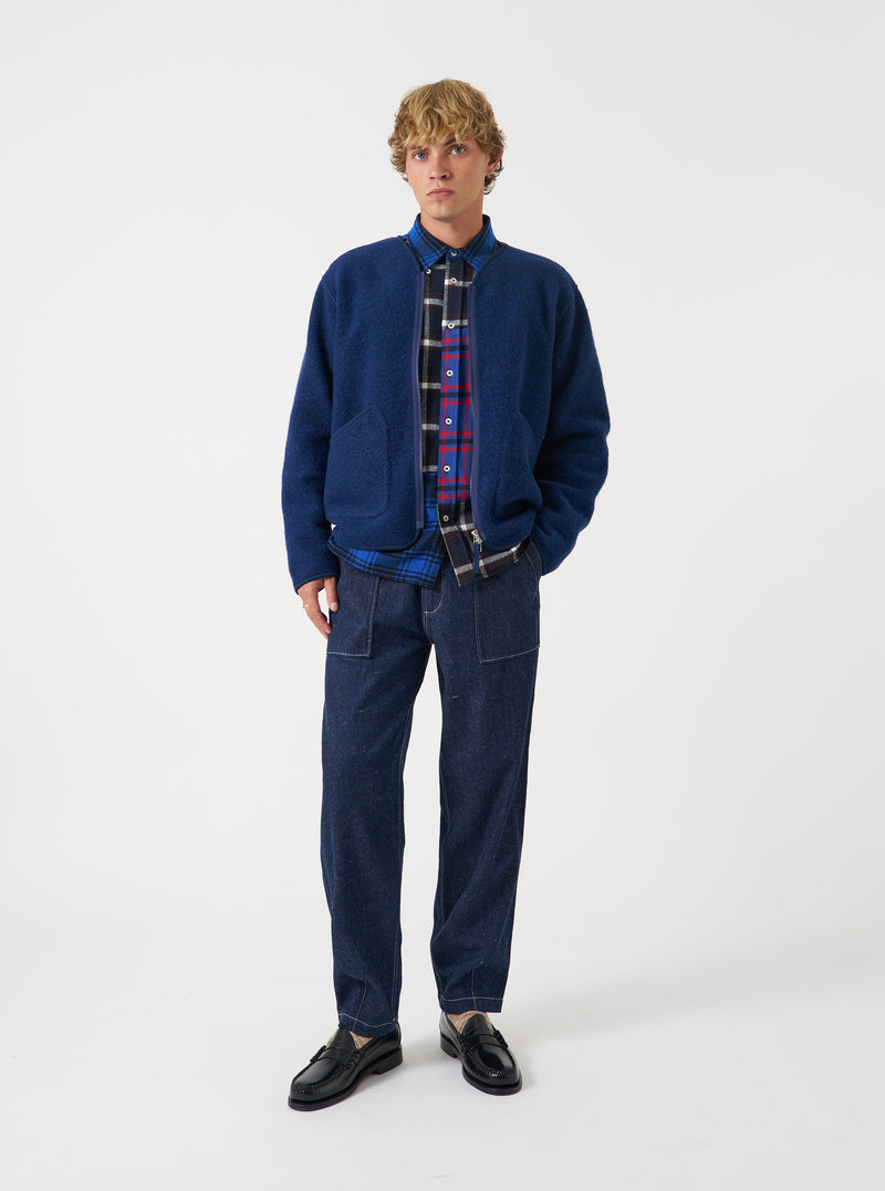Front view of a model wearing the Indigo Wool Fleece Zip Liner Jacket in a studio environment. The model faces forward, demonstrating the rich indigo blue wool fleece texture, collarless neckline, and zip closure.