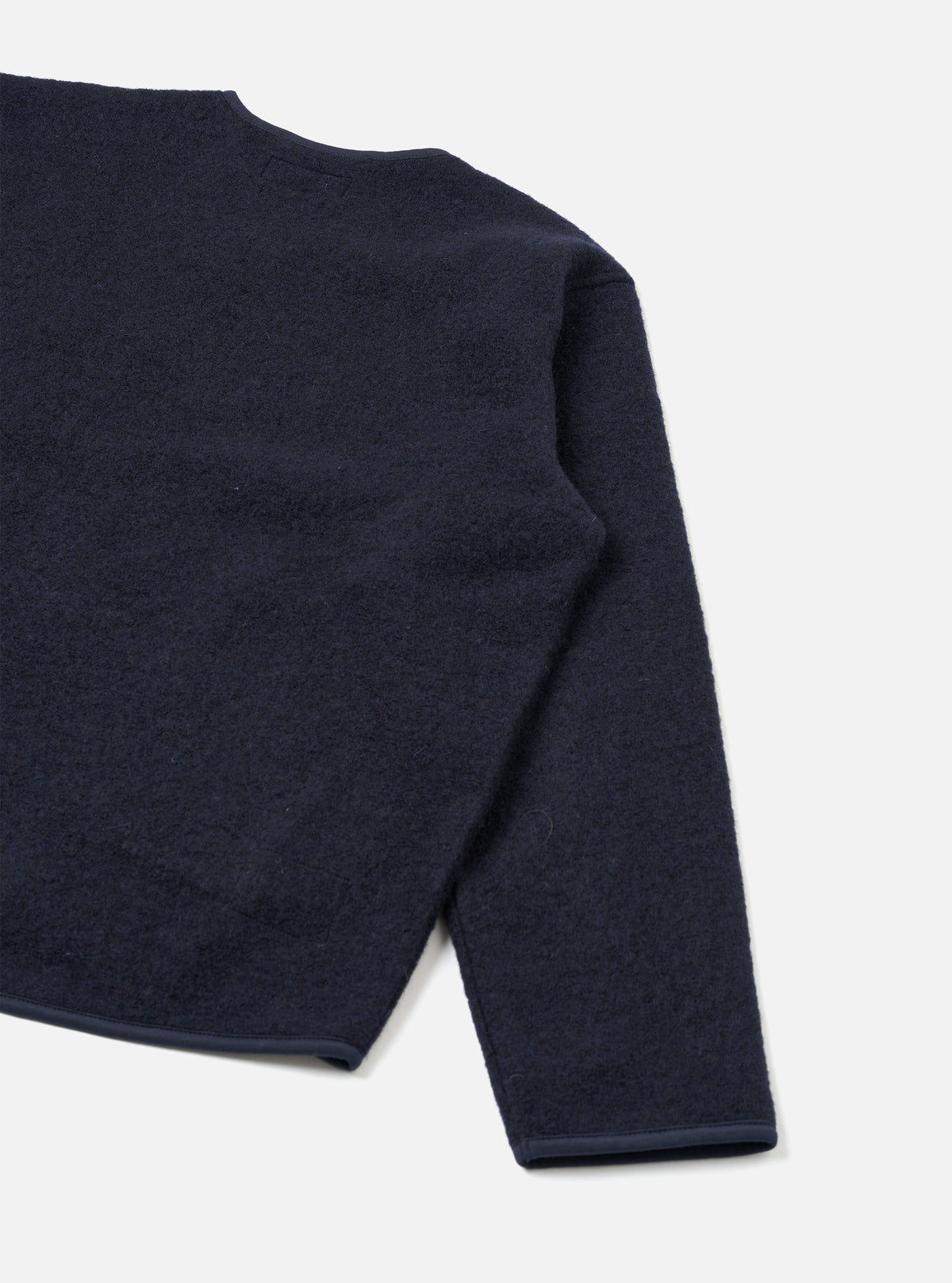 Rear view of the Navy Wool Fleece Zip Liner Jacket presented flat against a white backdrop. The shot showcases the clean back construction, navy blue wool fleece texture, and neatly edged sleeve cuffs and hem.
