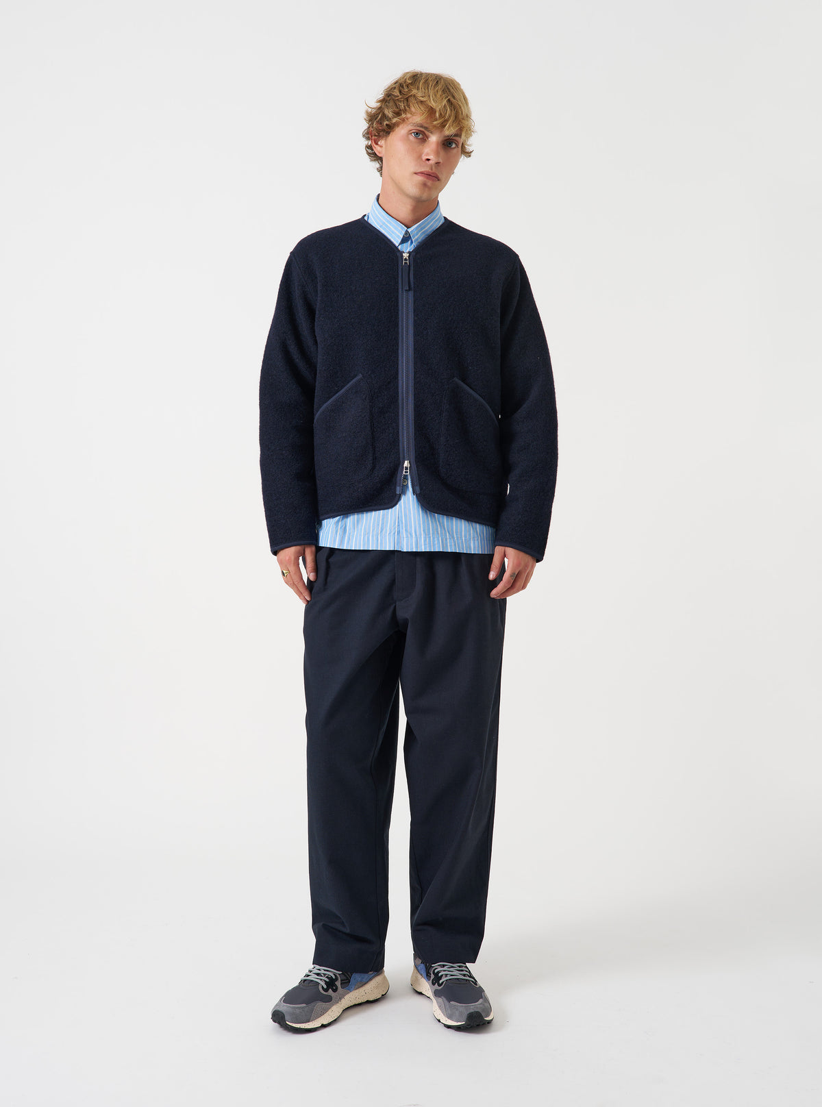 Front view of a model wearing the Navy Wool Fleece Zip Liner Jacket in a bright studio setting with a plain background. The model stands facing forward, showing the full length, zip front closure, and relaxed fit of the navy jacket.