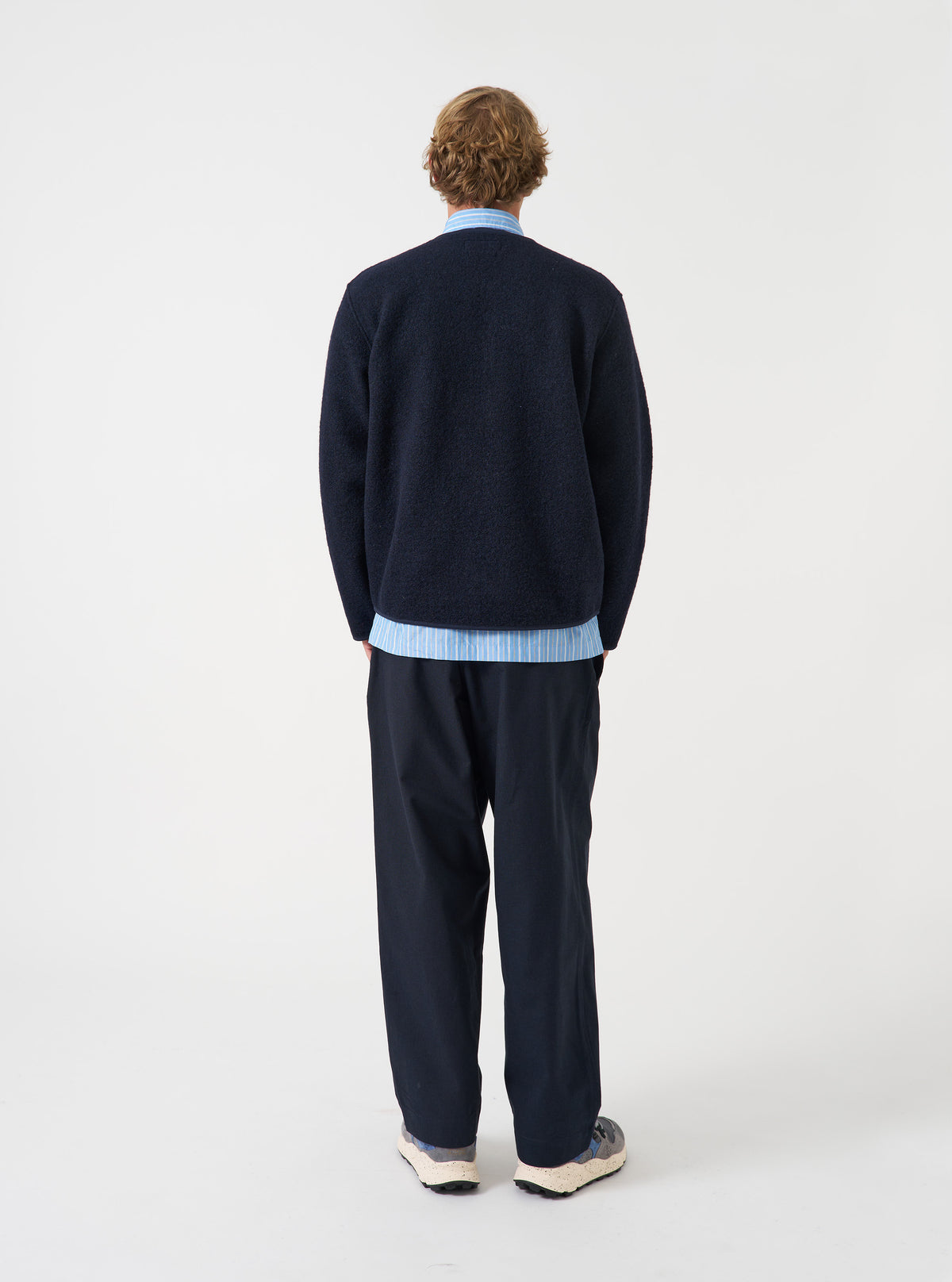 Three-quarter angle view of a model wearing the Navy Wool Fleece Zip Liner Jacket in a plain studio setting. Demonstrates the relaxed fit, side profile, and dark navy fleece texture as worn over casual clothing.