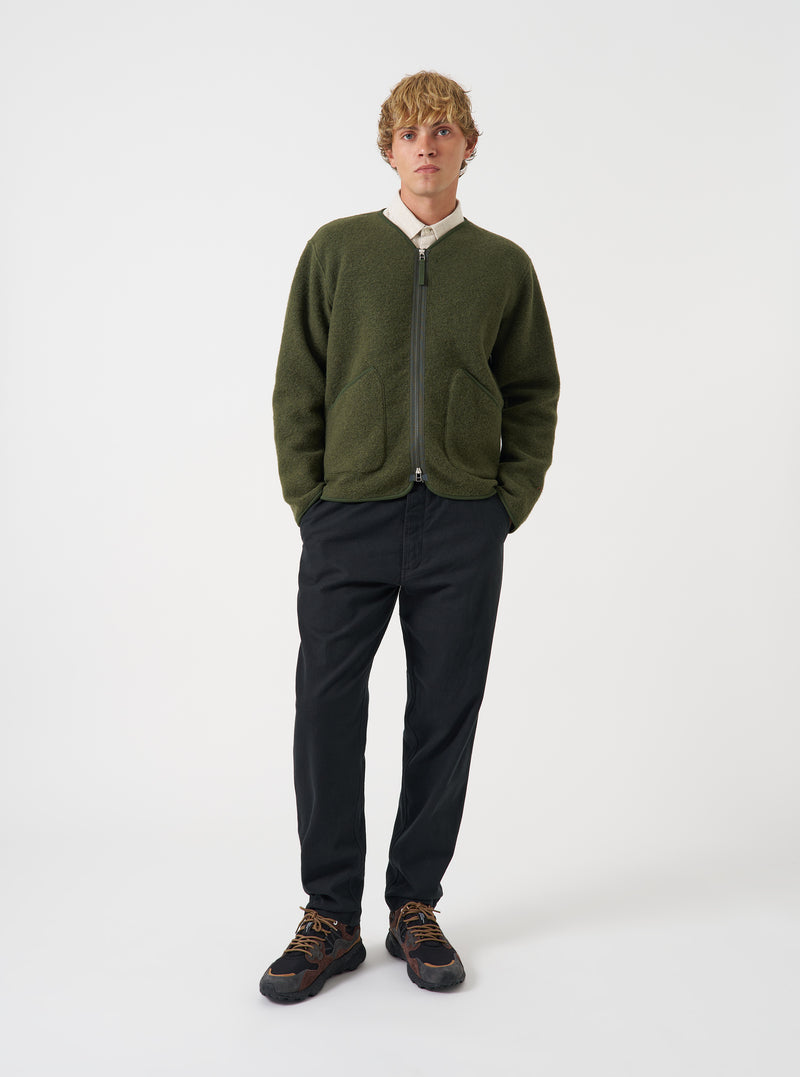Front view of a model wearing the Olive Wool Fleece Zip Liner Jacket standing in a minimal studio setting with a neutral backdrop. The model showcases the front zipper, comfortable fit, and olive fleece material in natural light.