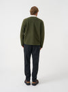 Angled side view of a model wearing the Olive Wool Fleece Zip Liner Jacket in a plain studio setting. Illustrates how the fleece jacket drapes naturally, highlighting the shoulder line, sleeve cut, and soft olive wool fabric.