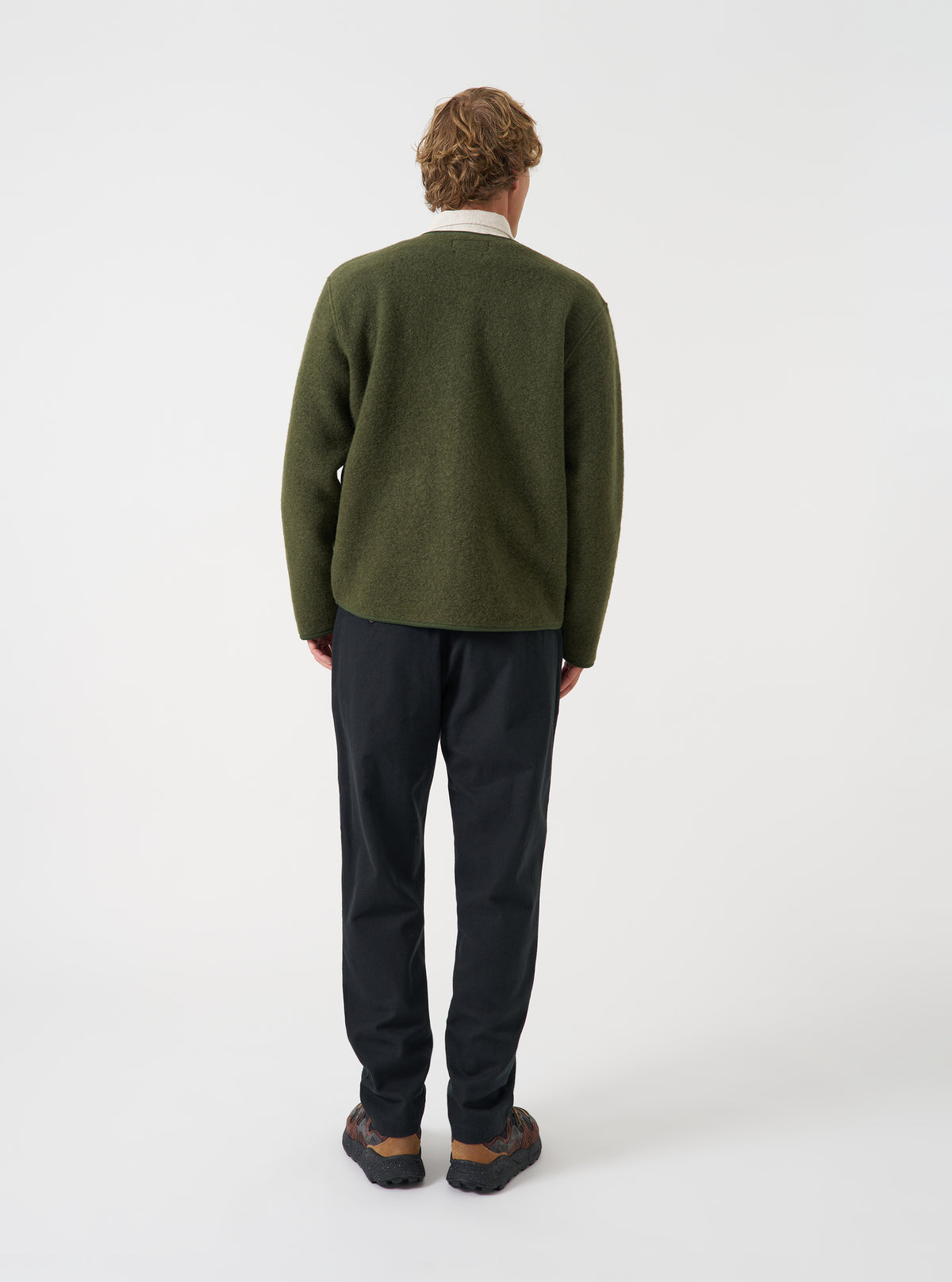 Angled side view of a model wearing the Olive Wool Fleece Zip Liner Jacket in a plain studio setting. Illustrates how the fleece jacket drapes naturally, highlighting the shoulder line, sleeve cut, and soft olive wool fabric.