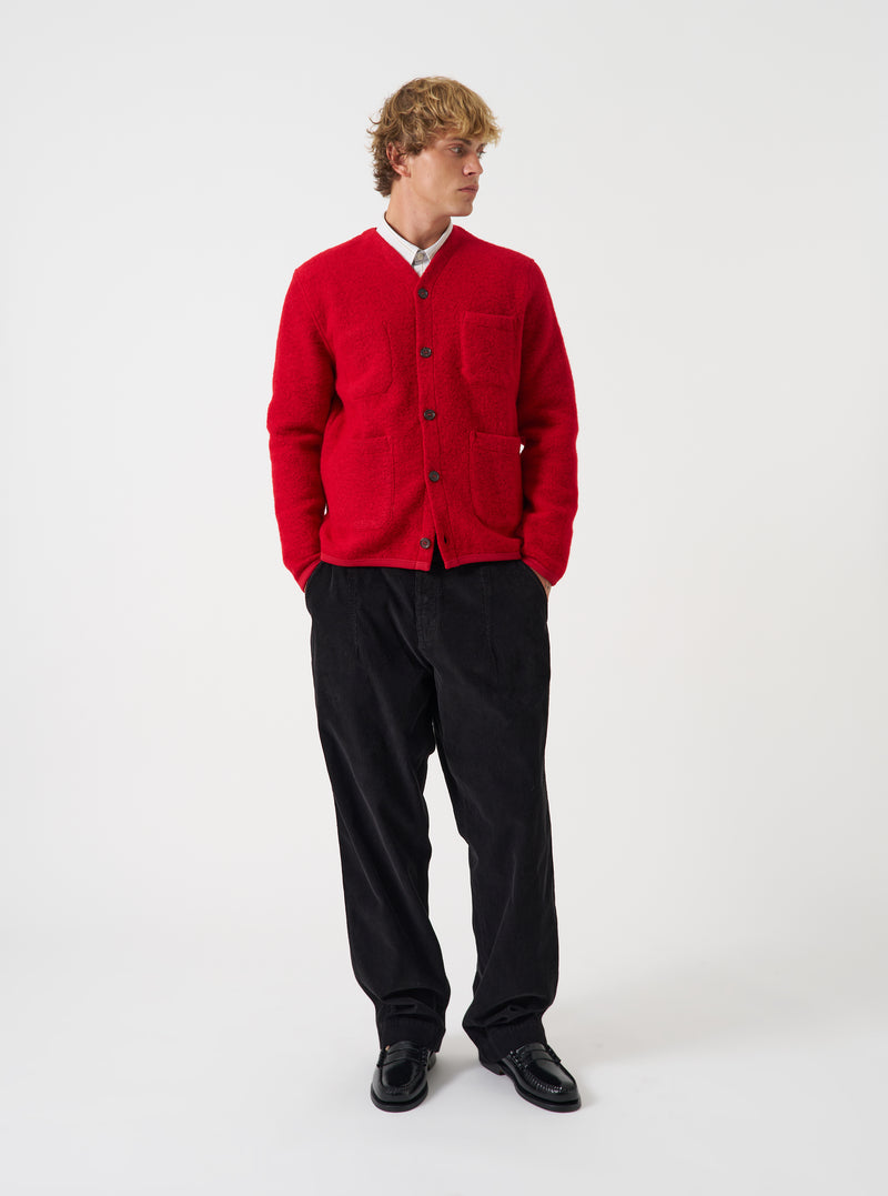 Front view of a model wearing the Scarlet Wool Fleece Cardigan in a clean studio space with a neutral backdrop. The model faces forward, showing the bright red wool fleece knit, button front closure, and V-neck cut.