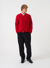 Front view of a model wearing the Scarlet Wool Fleece Cardigan in a clean studio space with a neutral backdrop. The model faces forward, showing the bright red wool fleece knit, button front closure, and V-neck cut.