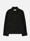 Black wool fleece uniform jacket laid flat on a white studio backdrop. Features a point collar, five dark buttons down the centre front, one chest patch pocket and two large lower patch pockets. The textured boiled wool fleece fabric is visible throughout. A Universal Works woven label sits inside the collar.