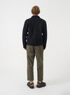 Angled view of a model wearing the Black Wool Fleece Uniform Jacket in a clean studio setting. Highlights the comfortable fit, soft black wool fleece material, shoulder construction, and overall profile of the jacket.