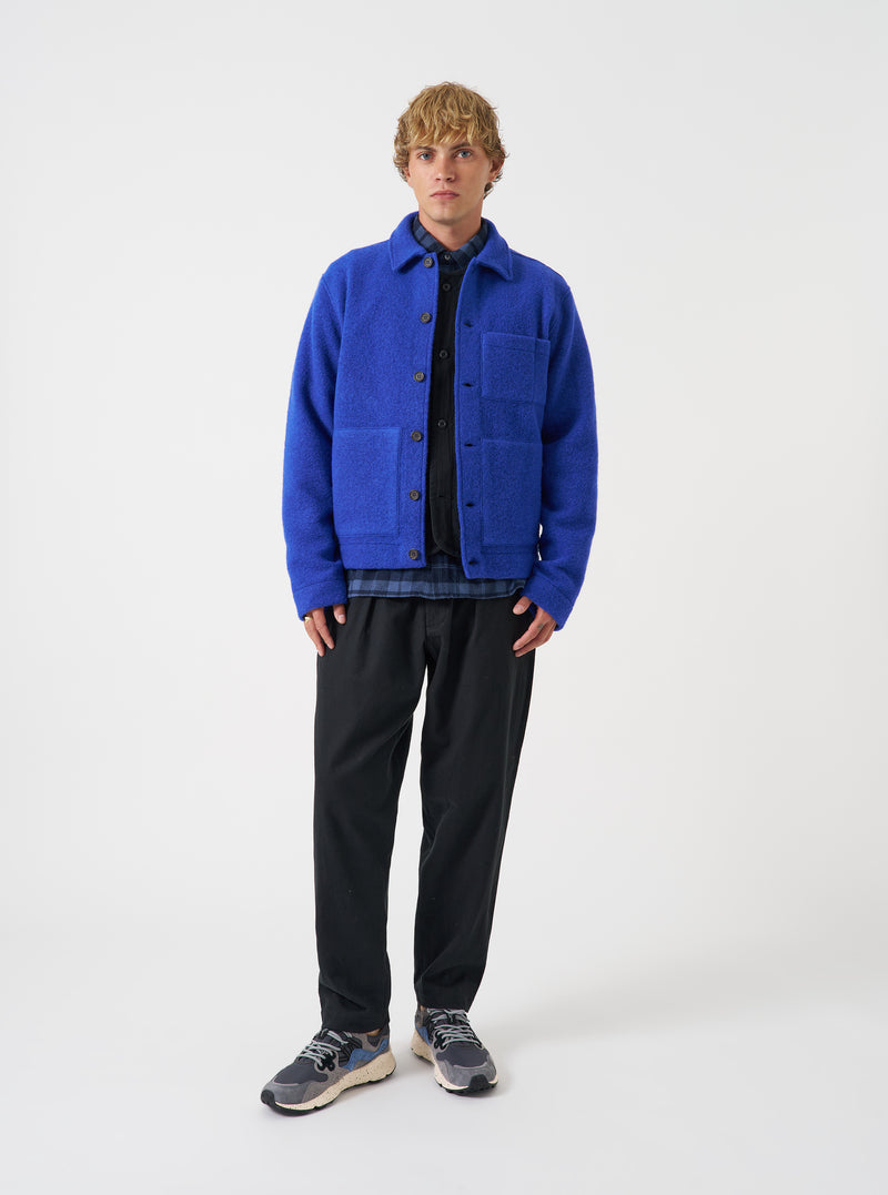 Front view of a model wearing the Blue Wool Fleece Uniform Jacket in a studio setting against a light background. The model faces forward to show the button-up front, structured collar, patch pockets, and rich blue color.