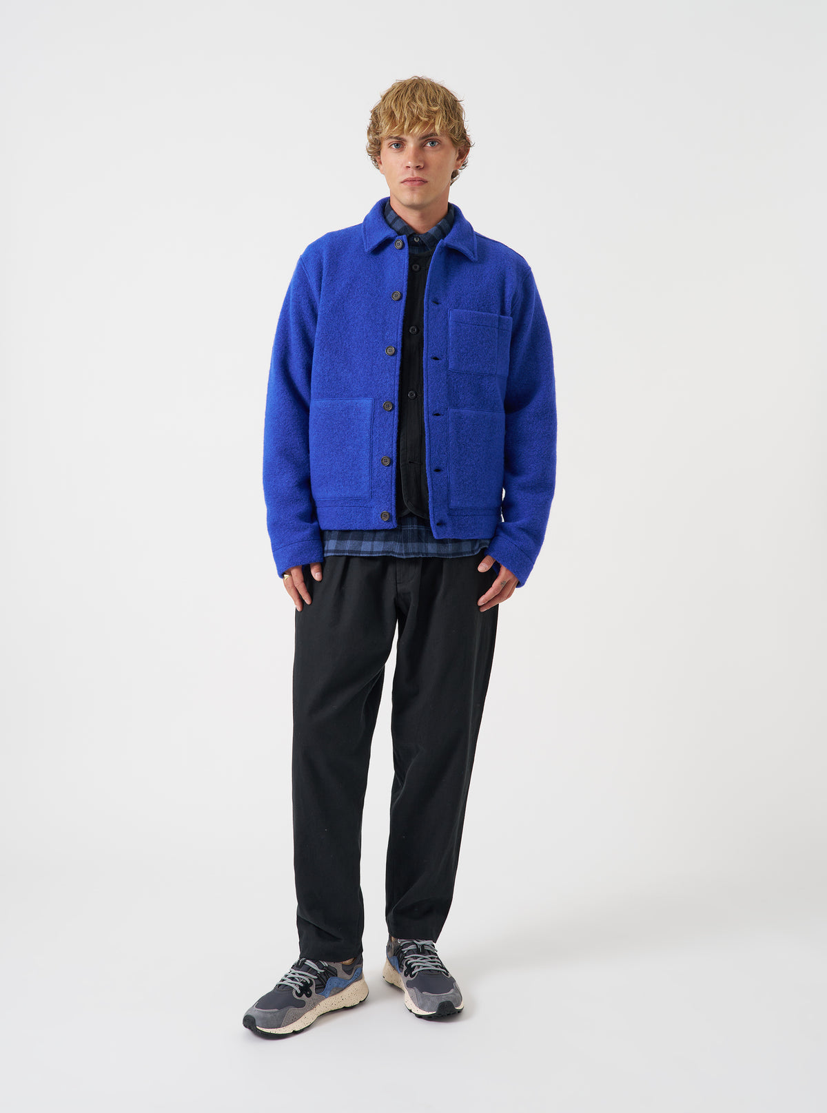 Front view of a model wearing the Blue Wool Fleece Uniform Jacket in a studio setting against a light background. The model faces forward to show the button-up front, structured collar, patch pockets, and rich blue color.