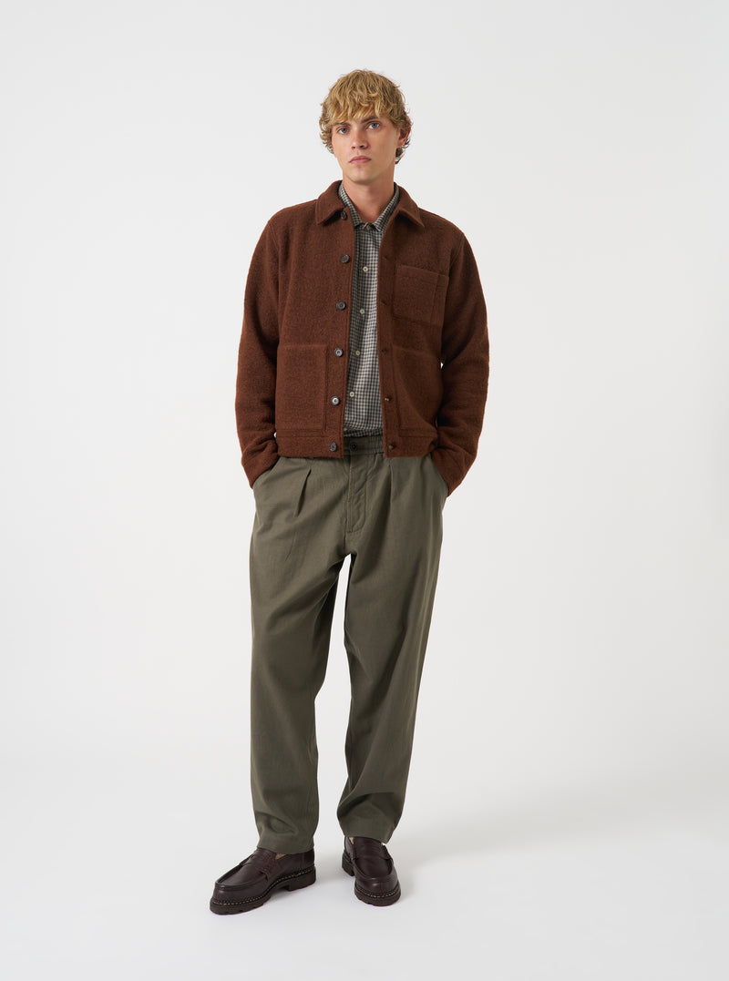 Front view of a model wearing the Cacao Wool Fleece Uniform Jacket against a plain light background. The model stands facing forward, highlighting the brown wool fleece material, button closure, and large front patch pockets.