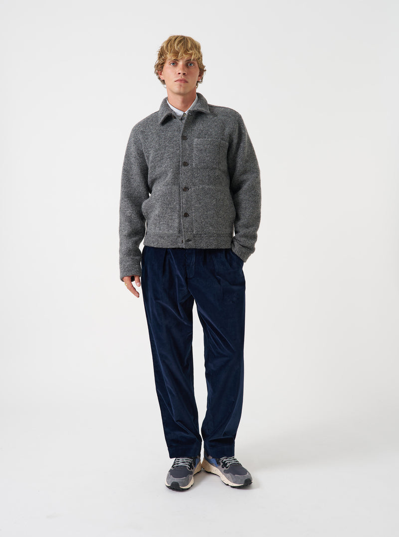 Front view of a model wearing the Grey Marl Wool Fleece Uniform Jacket against a plain studio background. The model stands facing front, showcasing the grey marl fleece texture, buttoned front placket, and patch chest pocket.