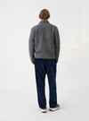 Back view of a model wearing the Grey Marl Wool Fleece Uniform Jacket against a plain light backdrop. The image highlights the clean back construction, shoulder fit, and soft grey marl textured wool fleece fabric.