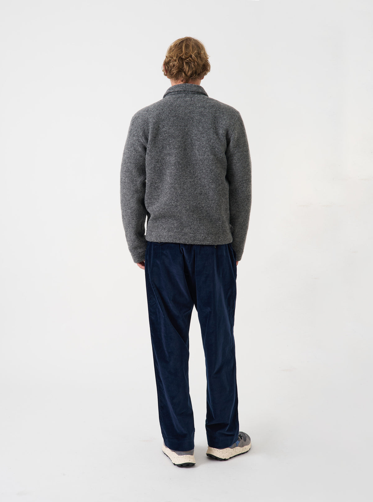 Back view of a model wearing the Grey Marl Wool Fleece Uniform Jacket against a plain light backdrop. The image highlights the clean back construction, shoulder fit, and soft grey marl textured wool fleece fabric.
