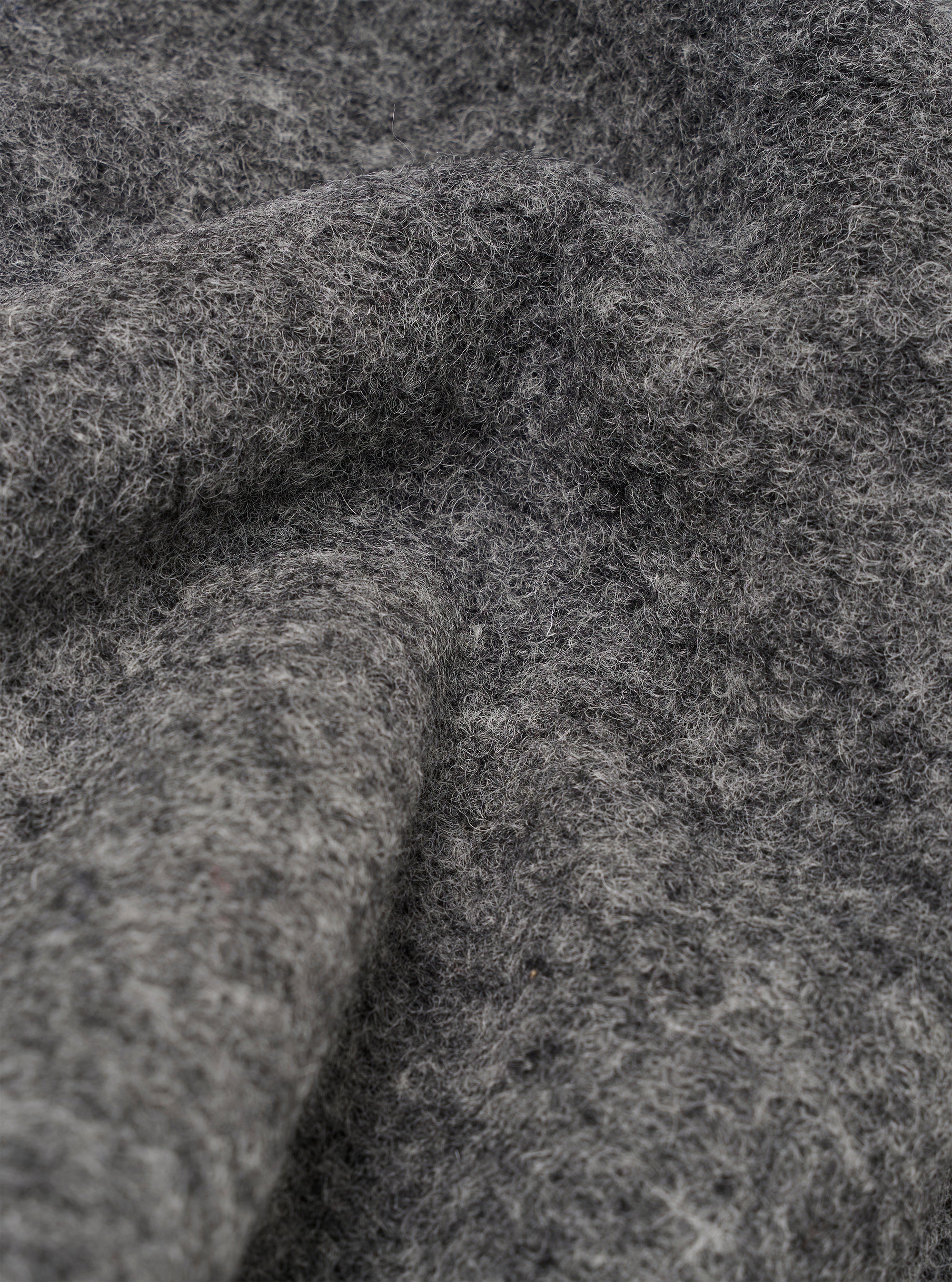 Close-up of the grey marl wool fleece fabric on the Uniform Jacket, showing the dense, brushed texture with fine fibres and a soft, chunky pile. Folds and curves in the material highlight the fabric's depth and volume. No background visible.