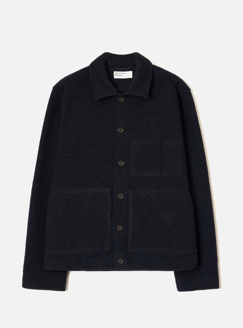 The Navy Wool Fleece Uniform Jacket is laid flat on a light grey seamless backdrop. Highlights include a spread collar, five dark horn buttons down the front, two large patch pockets on the chest and lower front, and ribbed trims at the hem and cuffs.