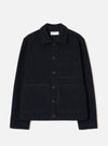 Navy wool fleece uniform jacket laid flat on a light grey seamless backdrop. Features a spread collar, five dark horn buttons down the centre front, two large patch pockets on the chest and lower front, and a ribbed hem and cuffs. The textured fleece has a dense, looped surface throughout.