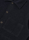 Close-up of a navy wool fleece uniform jacket showing the spread collar, single-breasted button placket with grey four-hole buttons, and a large patch pocket on the chest. The boiled wool texture is visible throughout. Plain white studio backdrop.