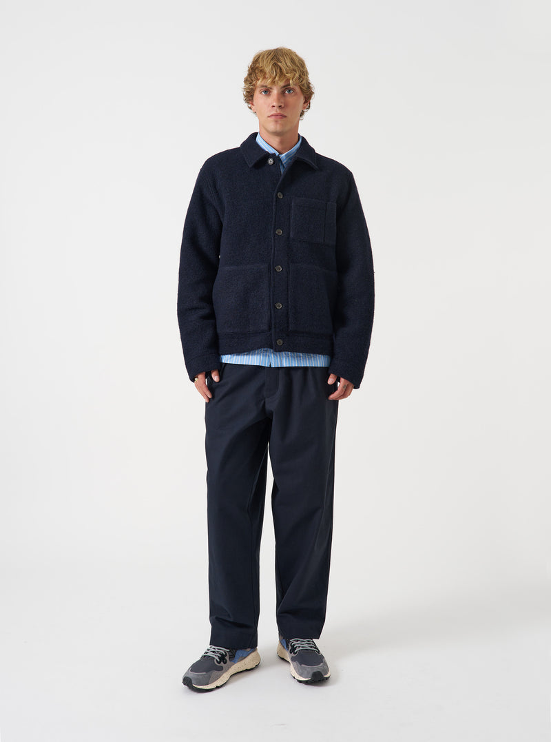 Front view of a model wearing the Navy Wool Fleece Uniform Jacket against a plain light backdrop. The model stands facing forward, displaying the dark navy wool fleece fabric, button front placket, and front patch pockets.